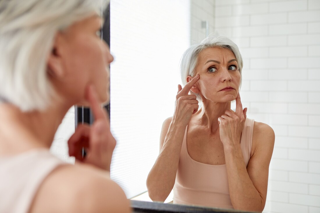 Woman looking at wrinkles in mirror.jpg