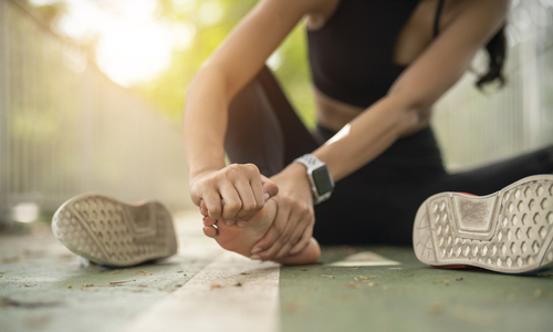 Woman sitting and holding front of foot in hands.jpg