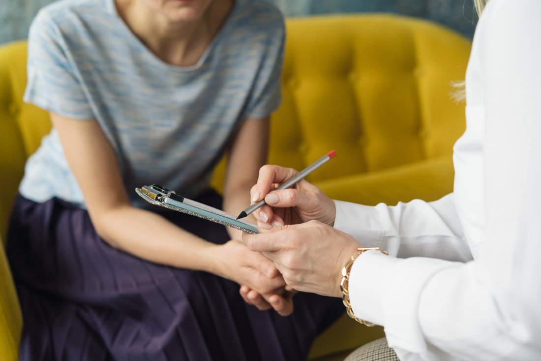 Person sitting in clinician office with doctor writing