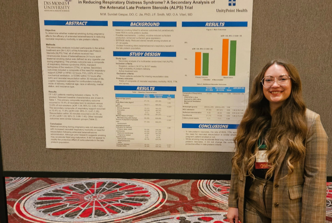 A resident smiling with her QI poster at a conference..jpg