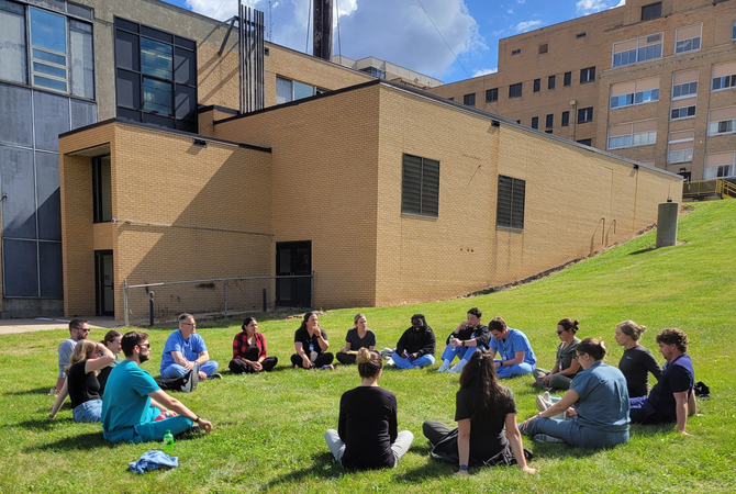 A group of residents sitting on the ground outside of Lutheran Hospital in a circle..jpg