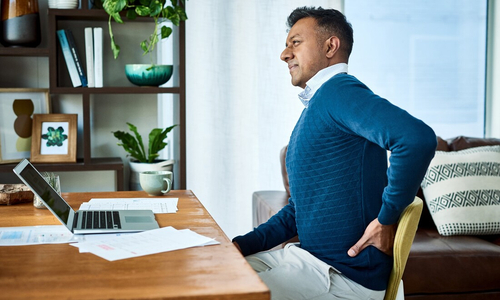 Man in bed holding lower back in pain.jpg