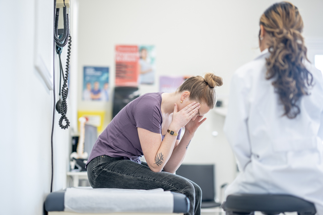 Doctor talking to patient holding head in pain.jpg