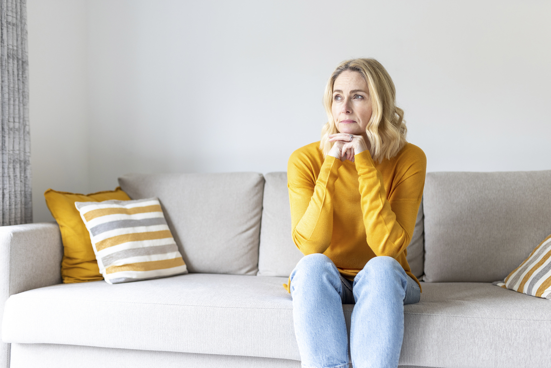 Woman sitting on couch thinking