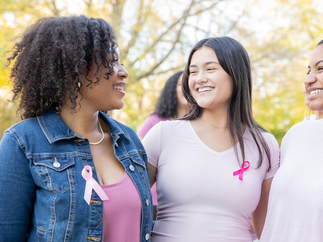 Smiling women wearing pink breast cancer ribbons on shirts.jpg