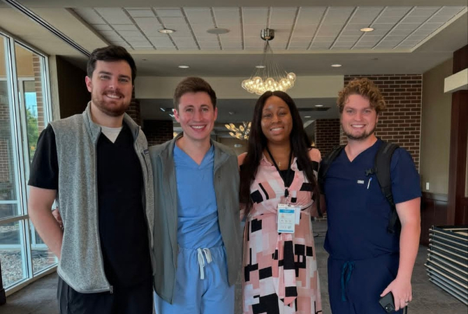 Four family medicine residents standing in hallway smiling.jpg