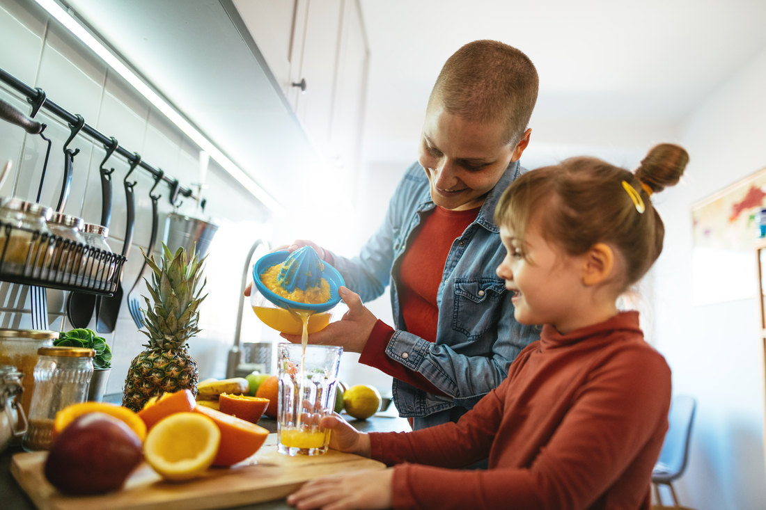 Woman making orange juice with child