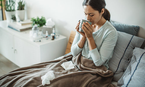 Sick woman drinking tea in bed.jpg
