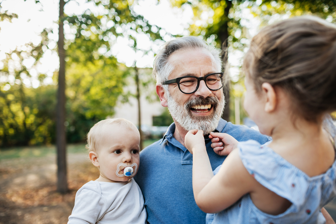 Grandfather holding two grandkids outside