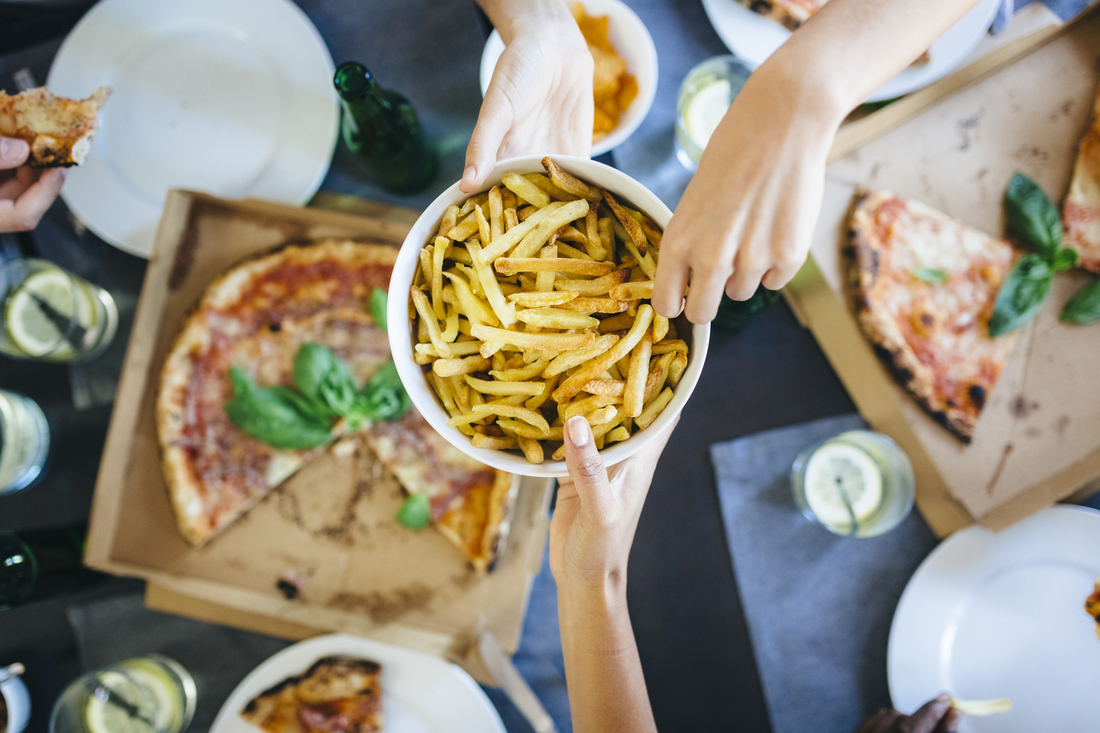 Hand reaching for french fries and pizza.jpg