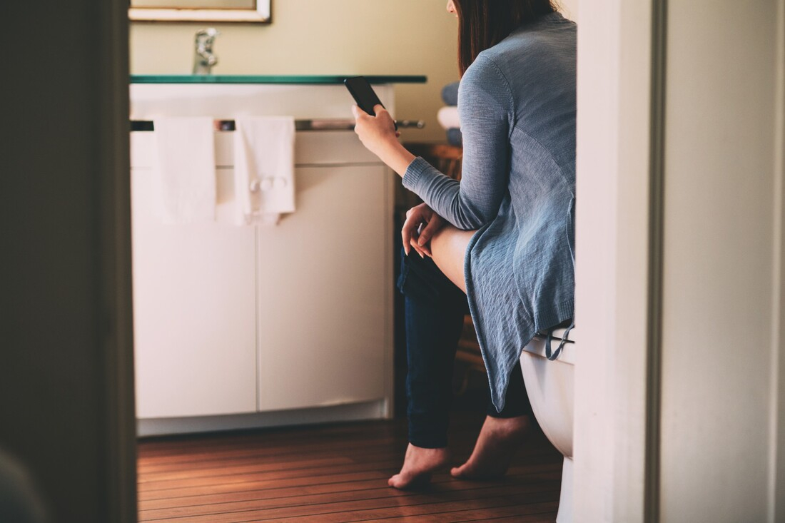 Woman looking at phone while using toilet.jpg