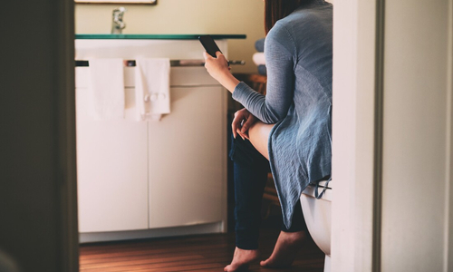 Woman looking at phone while using toilet.jpg
