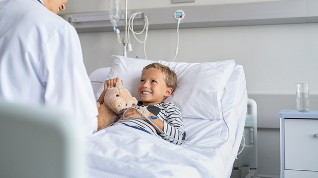 Happy boy in hospital bed with teddy bear.jpg