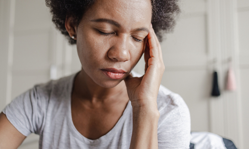 Young women holding her head while looking down experiencing fatigue