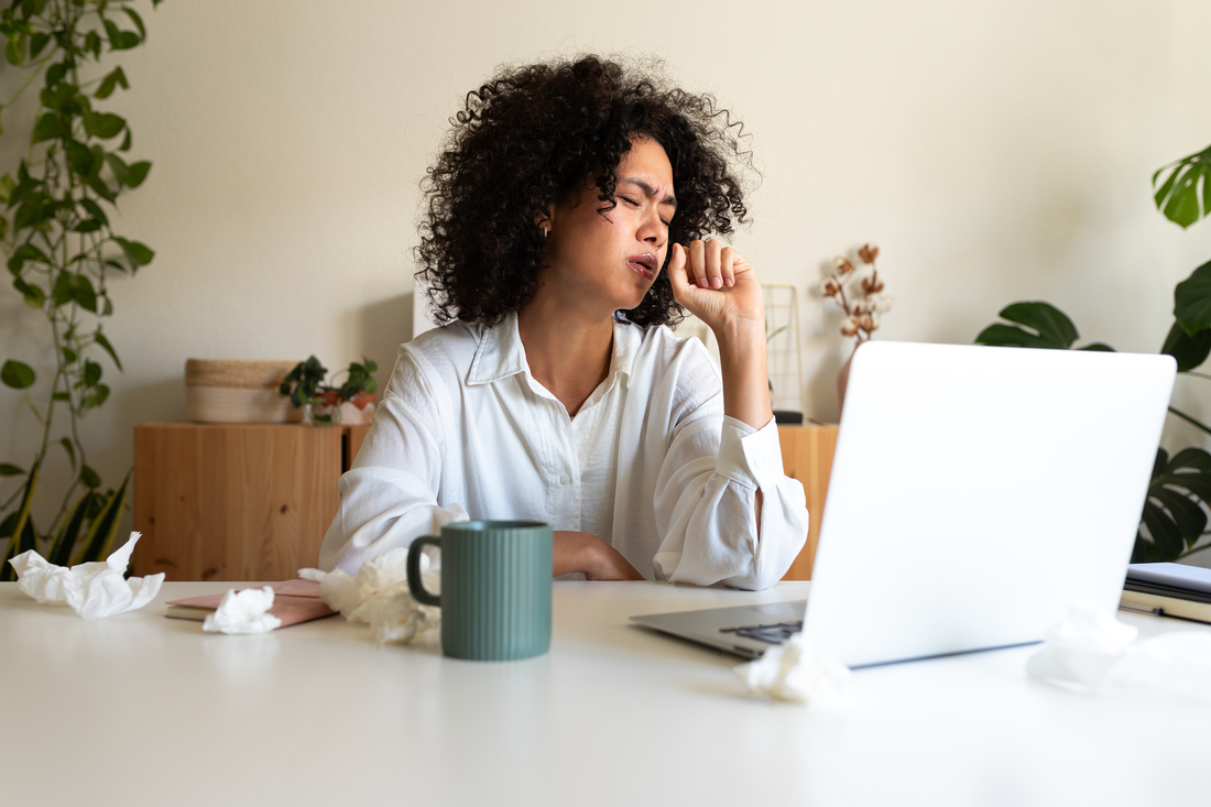 Sick woman coughing at desk.jpg