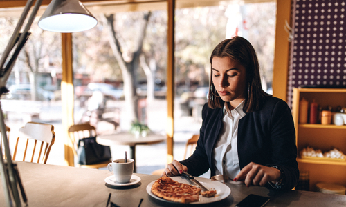 Woman sitting at table looking down at food 