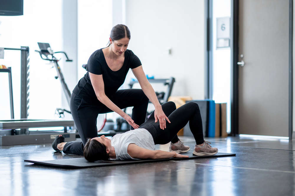 Physical therapist helping woman do pelvic floor therapy kegel exercise