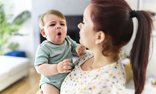 Mother holding sick baby coughing