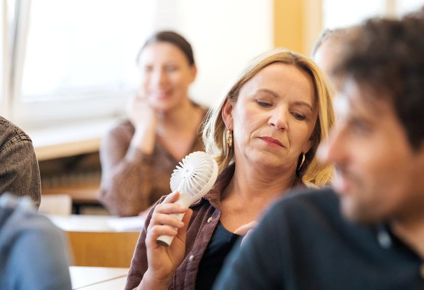Woman with hot flash using electric hand-fan.jpg