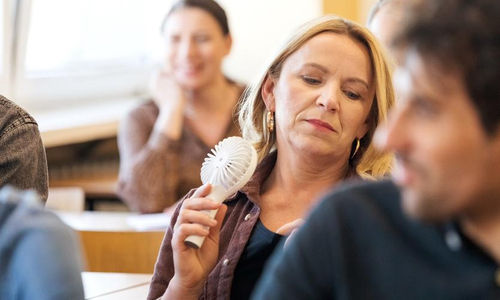 Woman with hot flash using electric hand-fan.jpg