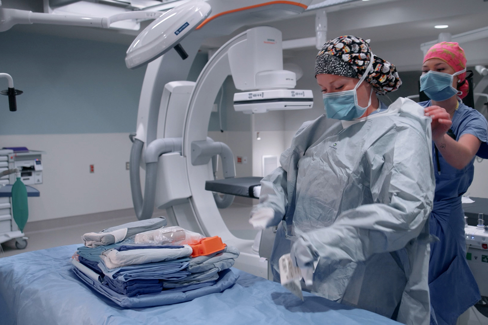 Healthcare workers in operating room gowning for procedure