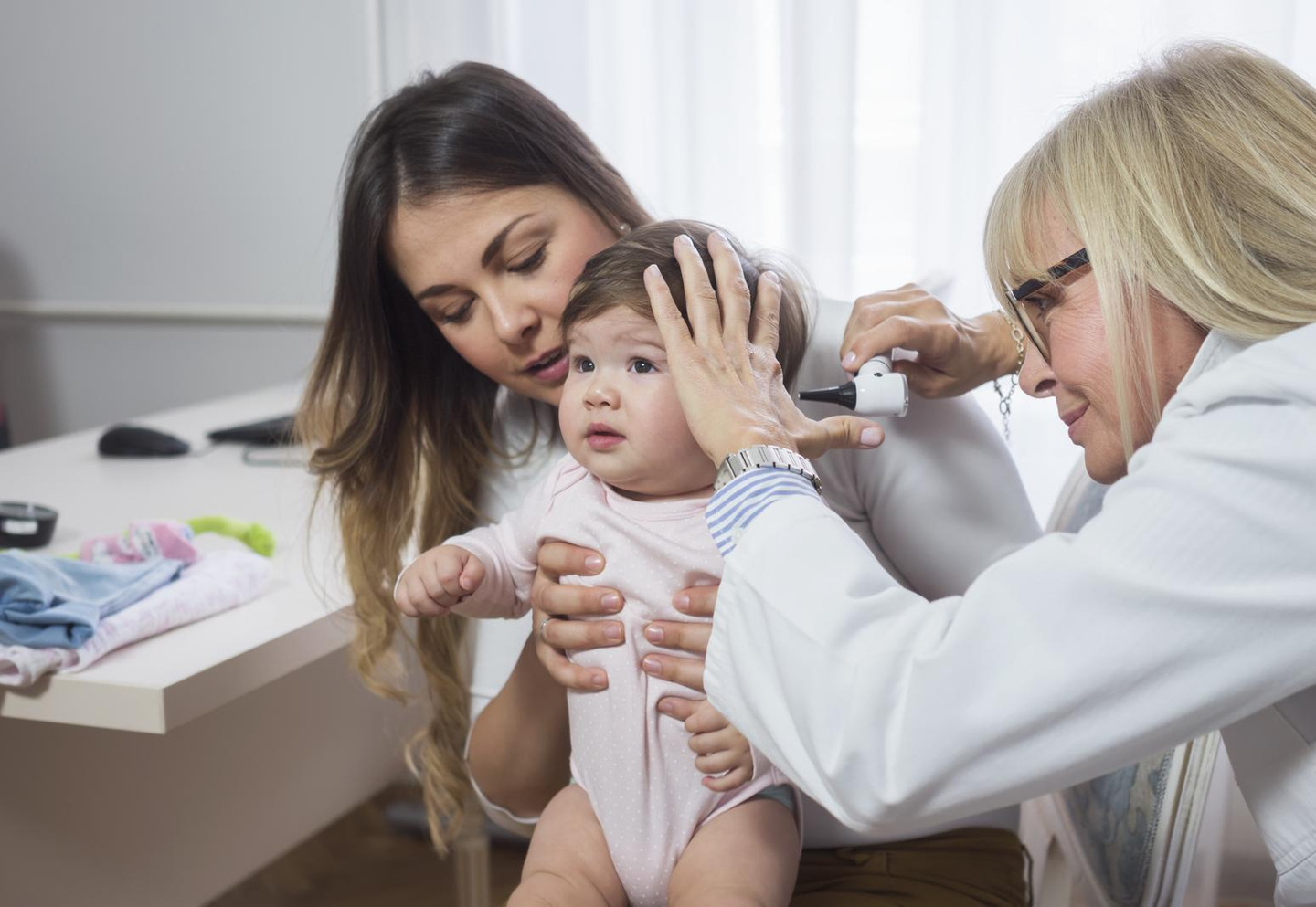 Doctor examining baby with Otoscope