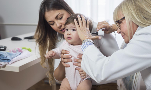 Doctor examining baby with Otoscope