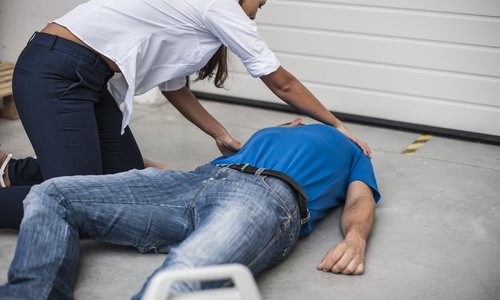 Woman rolling man onto his side lying on ground.jpg