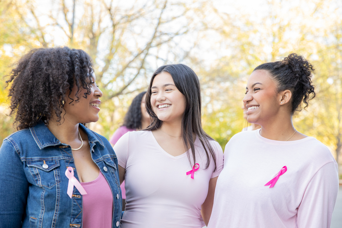 Smiling women wearing pink breast cancer ribbons on shirts.jpg