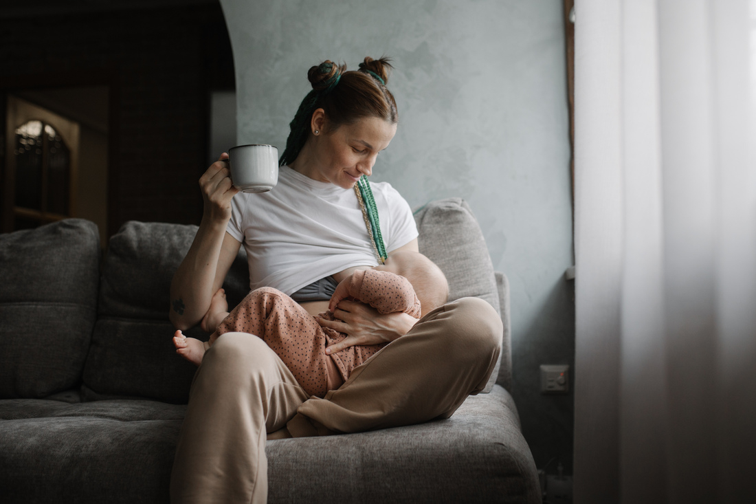 Mother holding a mug while breastfeeding baby.jpg