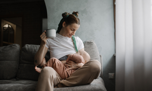 Mother holding a mug while breastfeeding baby.jpg