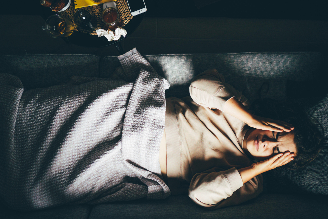 Woman in bed with headache holding head in pain.jpg
