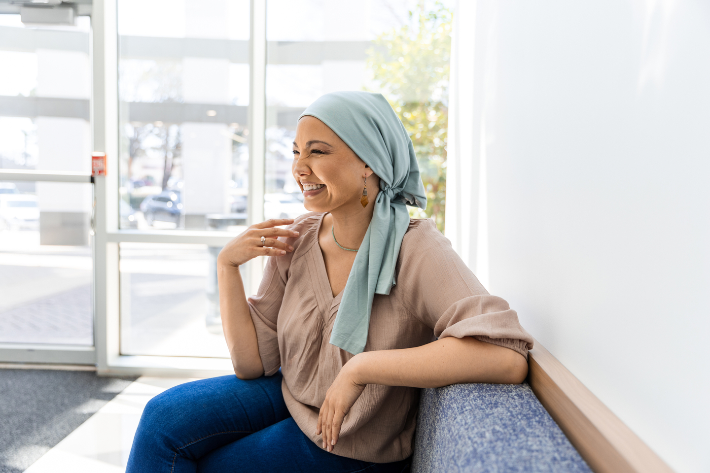 Female cancer patient sitting in clinic lobby smiling