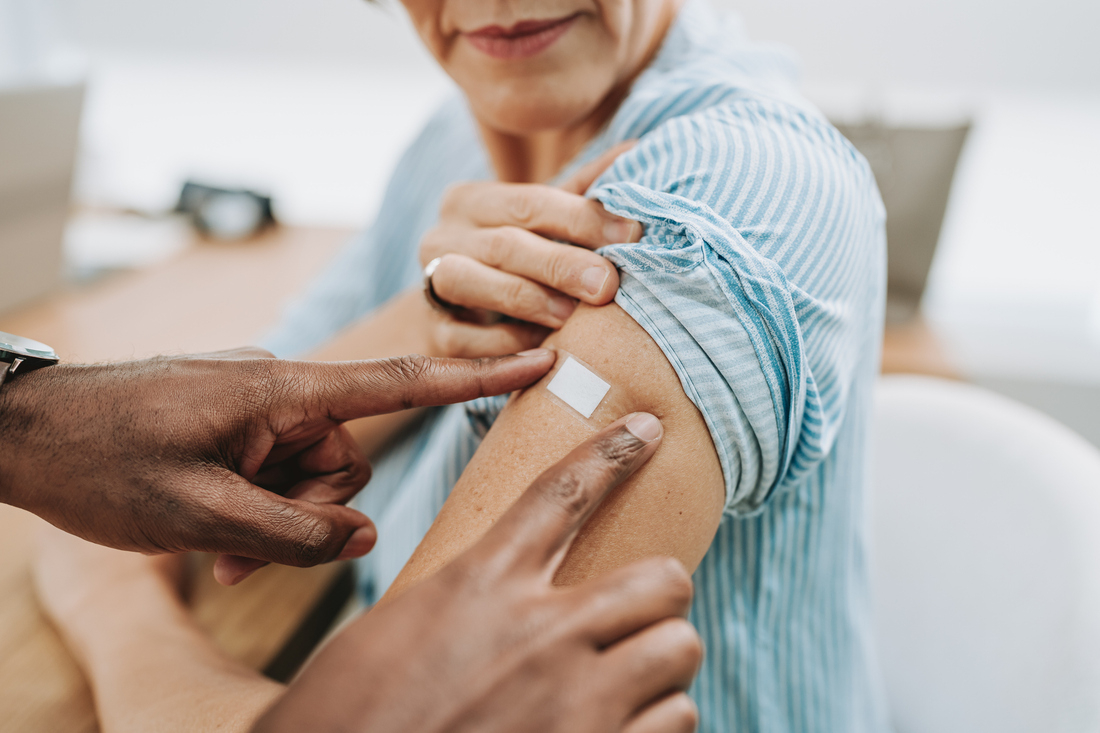 Hand placing bandaid on woman's arm.jpg