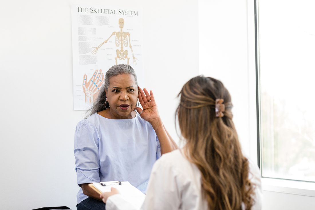 Patient talking to doctor at ear exam, hearing screening
