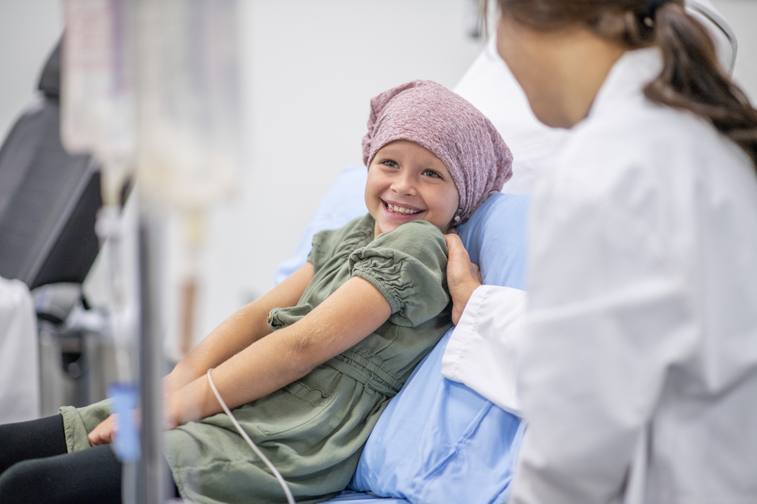 Doctor talking to child cancer pateient in hospital bed.jpg