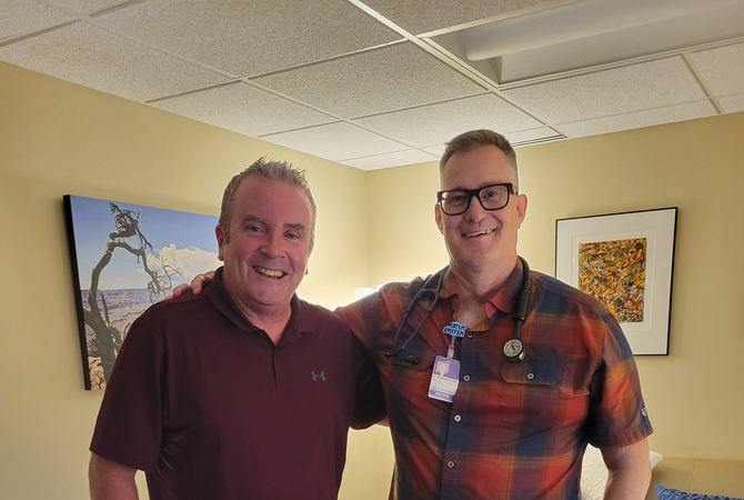 Two faculty in an office smiling at the camera..jpg