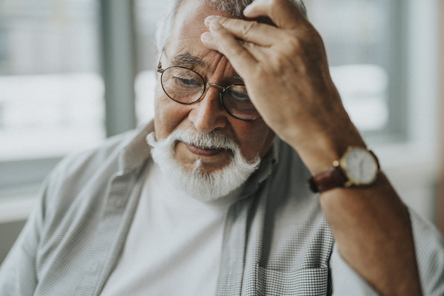 Older adult holding forehead with a headache, illustrating possible warning signs and symptoms of a silent stroke