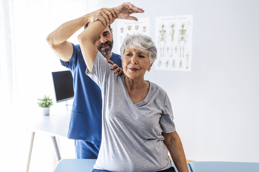 Clinician stretching womans arm overhead