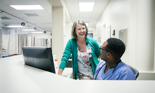 Doctor and nurse laughing by computer in ER.jpg