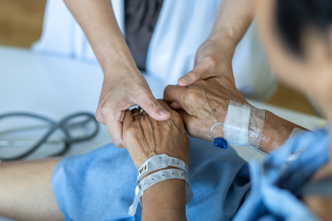 Healthcare worker holding hands of hospice patient