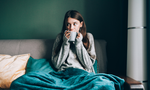 Woman with hot drink sitting under blanket.jpg
