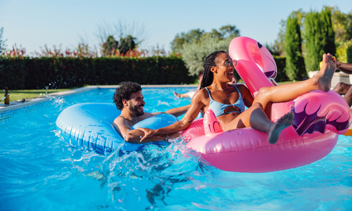 Smiling people using pool floaties in an outdoor pool.jpg